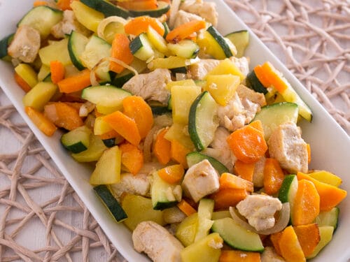 Gebratenes Hühnerfleisch, Zucchini, Karotten und Kartoffeln auf einem weißen Teller.