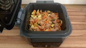 Hähnchenbrust mit Gemüse aus der Heißluftfritteuse 8 Gewürfeltes Hähnchen, Karotten und Zucchini in einem Frittierkorb, bereit für die Zubereitung von Hähnchen mit Gemüse aus der Heißluftfritteuse.