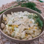 Cremiger Nudelsalat mit Hähnchen mit Mais, Gurken und Dill in einer Schüssel.