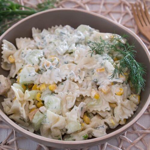 Schüssel mit cremigem Nudelsalat mit Huhn, Mais, Gurken und Dill.