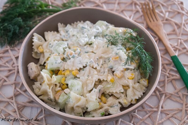 Schüssel mit cremigem Nudelsalat mit Huhn, Mais, Gurken und Dill.