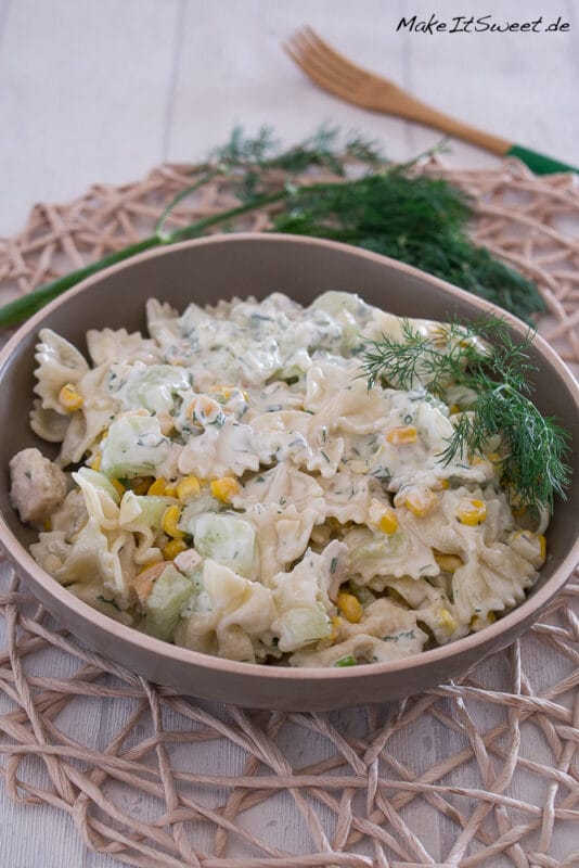 Cremiger Nudelsalat mit Hähnchen mit Mais, Gurken und Dill in einer Schüssel.