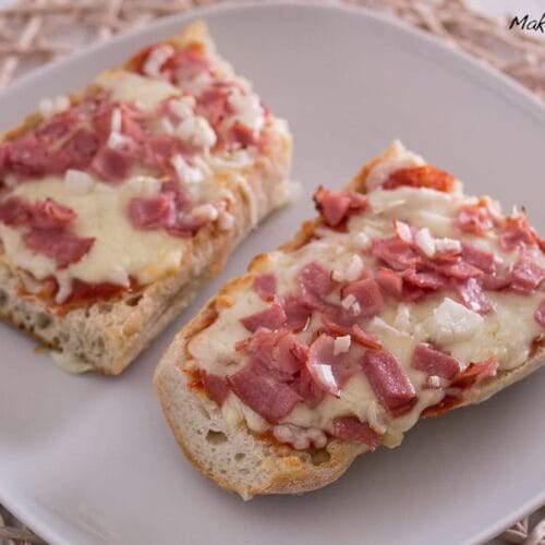 Zwei selbstgemachte Pizza Baguette aus der Heißluftfritteuse mit geschmolzenem Käse, Schinkenwürfeln und Zwiebeln.