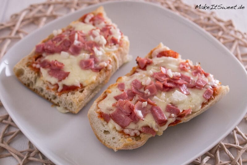 Zwei selbstgemachte Pizza Baguette aus der Heißluftfritteuse mit geschmolzenem Käse, Schinkenwürfeln und Zwiebeln.