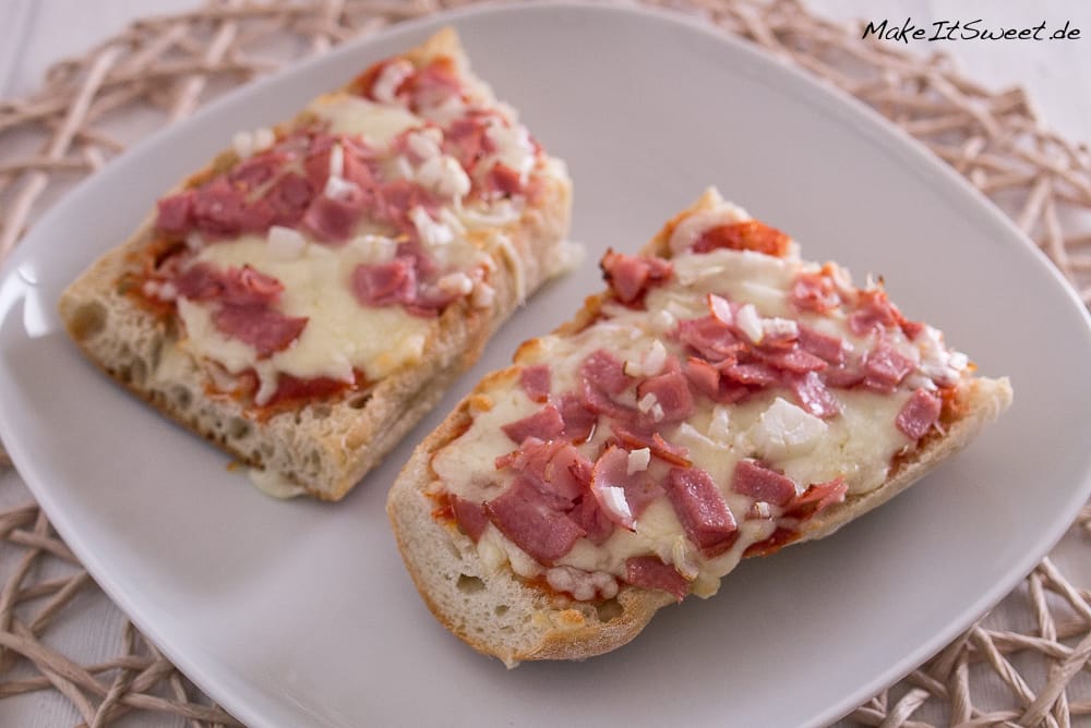 Zwei selbstgemachte Pizza Baguette aus der Heißluftfritteuse mit geschmolzenem Käse, Schinkenwürfeln und Zwiebeln.