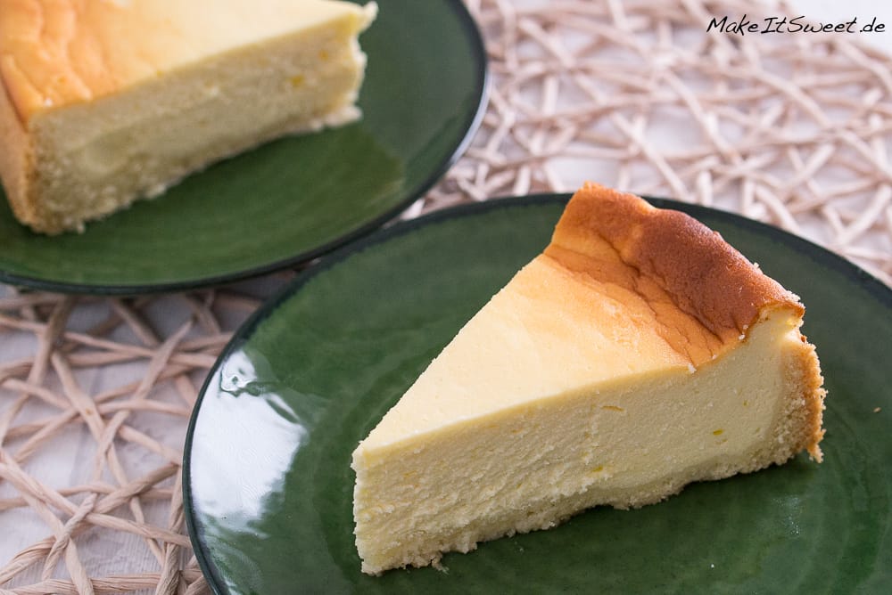 Zwei Stücke Käsekuchen auf grünen Tellern.