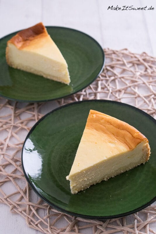Einfacher, zarter Käsekuchen 2 Zwei Stücke luftiger Käsekuchen auf grünen Tellern.