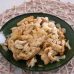 Hähnchen geschnetzeltes aus der Heißluftfritteuse mit Zwiebeln Hähnchenstreifen und angebratene Zwiebeln auf einem grünen Teller.