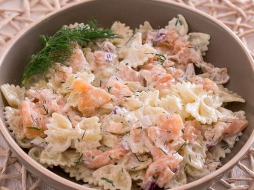 Nudeln mit Joghurt Soße, Räucherlachs, Dill und Zwiebeln in einer Schüssel.