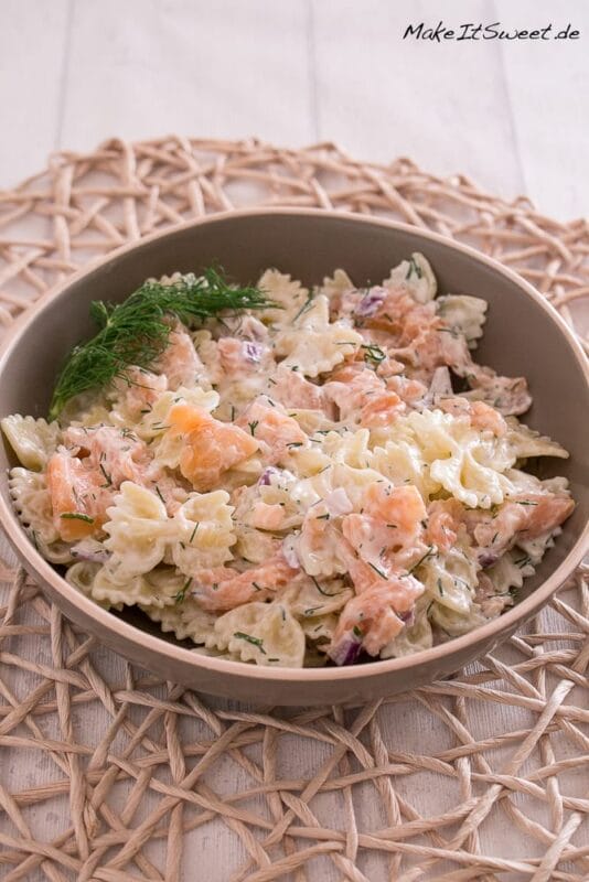 Nudeln mit Joghurt Soße, Räucherlachs, Dill und Zwiebeln in einer Schüssel.