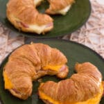 Croissant mit Schinken und Käse aus der Heißluftfritteuse auf grünen Tellern.