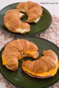 Croissant mit Schinken und Käse aus der Heißluftfritteuse 5 Croissant mit Schinken und Käse aus der Heißluftfritteuse auf grünen Tellern.